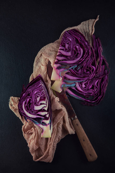 red cabbage cut in half with napkin and kitchen knife on a slate plate kitchen background - Valokuva, kuva