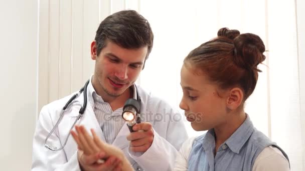 A nice little girl is sitting quietly while the doctor examines her - Video