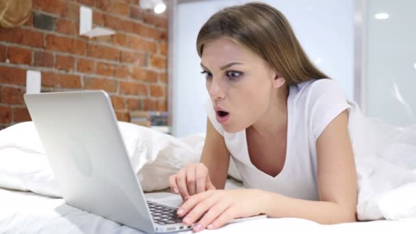 Frau im Bett schockiert über Ergebnisse auf Laptop und wundert sich - Filmmaterial, Video