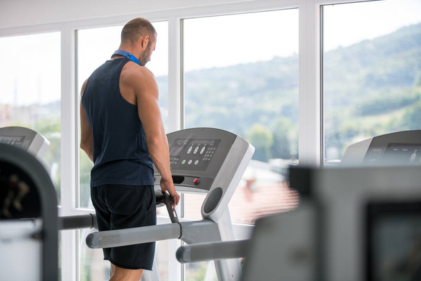 Young man in sportswear running on treadmill at gym - Fotó, kép