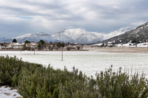 Uitzicht op het platteland en de met sneeuw bedekte bergen in een winter op een bewolkte dag (Griekenland, regio Arcadia) - Foto, afbeelding