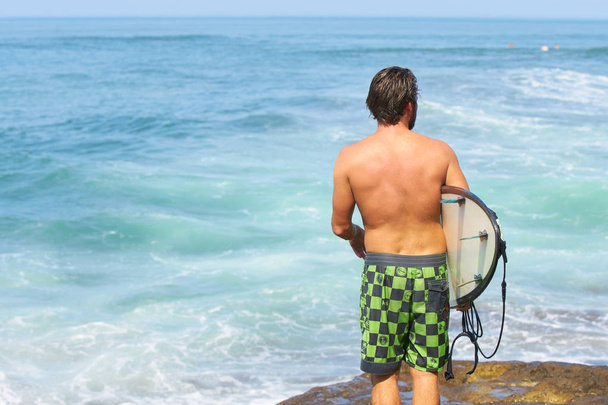Een surfer met zijn surfplank naar de golven gaan - Foto, afbeelding