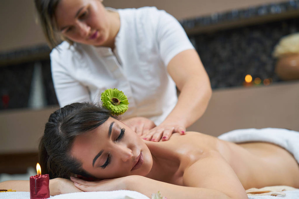 Mujer Spa. Mujer disfrutando relajante masaje de espalda en el centro de spa de cosmetología. Cuidado del cuerpo, Cuidado de la piel, Bienestar, Bienestar, Concepto de tratamiento de belleza
. - Foto, imagen