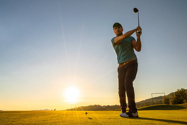 Man is playing golf during sunset - Foto, afbeelding