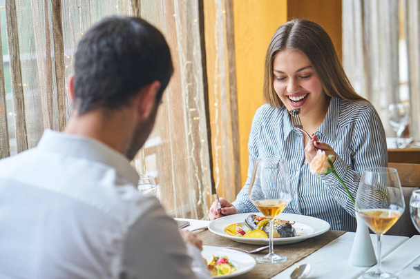 φαγητό, Χριστούγεννα, αργίες και οι άνθρωποι έννοια - χαμογελώντας ζευγάρι τρώει κυρίως πιάτο στο εστιατόριο - Φωτογραφία, εικόνα