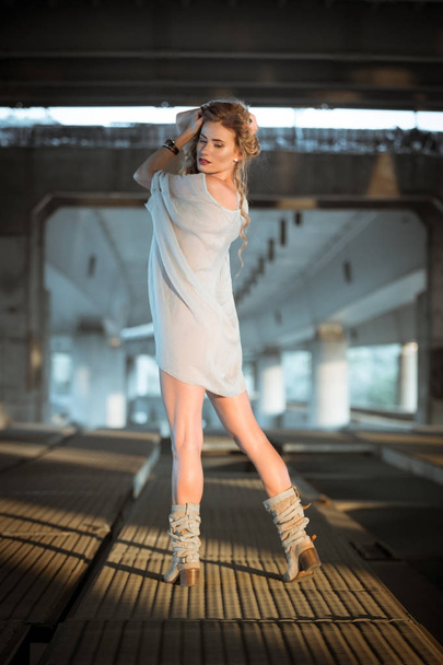Beautiful curly young woman standing on industrial bridge locati - Photo, image