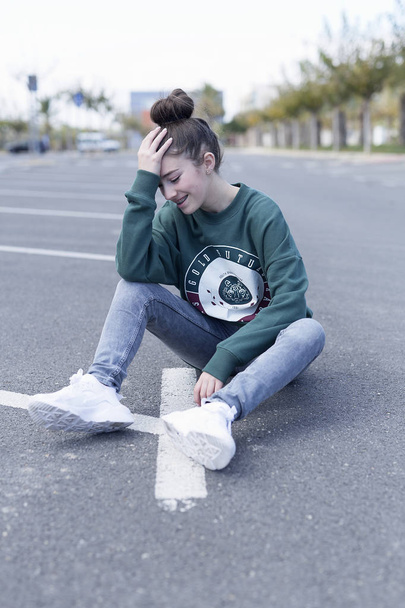 Teen girl sitting on the floor of a parking garage. - Photo, Image