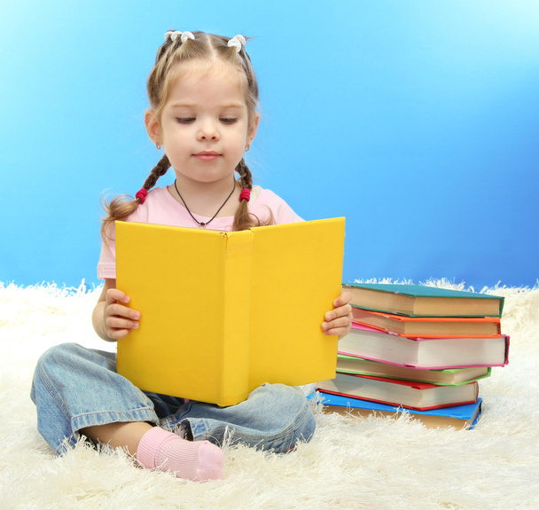 mignonne petite fille avec des livres colorés, sur fond bleu
 - Photo, image