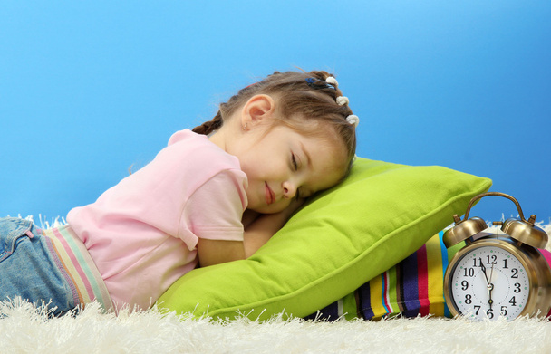 cute little girl sleeping on colorful pillows, on blue background - Foto, immagini