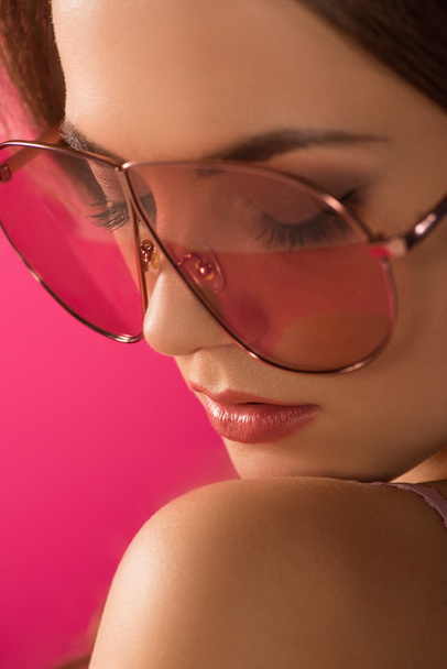 csukott szemmel elszigetelt rózsaszín napszemüveg a vonzó lány portréja  - Fotó, kép
