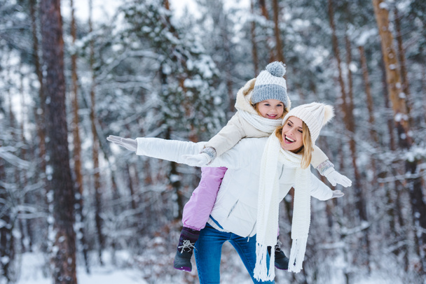 весела мати і маленька дитина збираються разом у зимовому парку
 - Фото, зображення