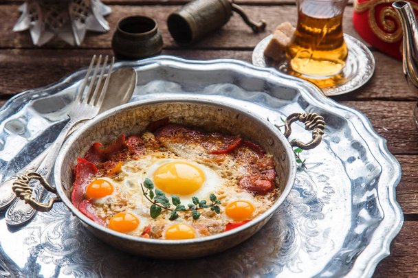 Традиционный турецкий завтрак с яйцами и пастирмой, с чаем и металлической посудой
 - Фото, изображение