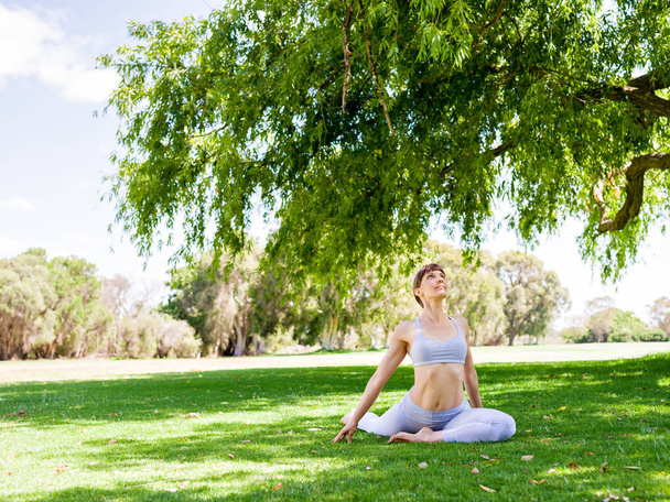 Young woman practicing yoga in the park - Foto, afbeelding