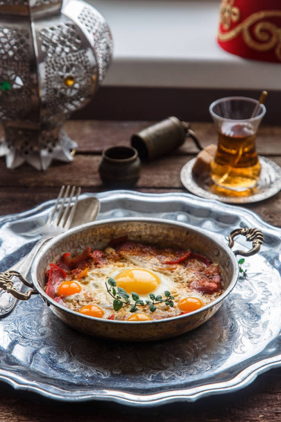 Медная сковорода с жареными яйцами и сосисками, в турецком стиле
 - Фото, изображение