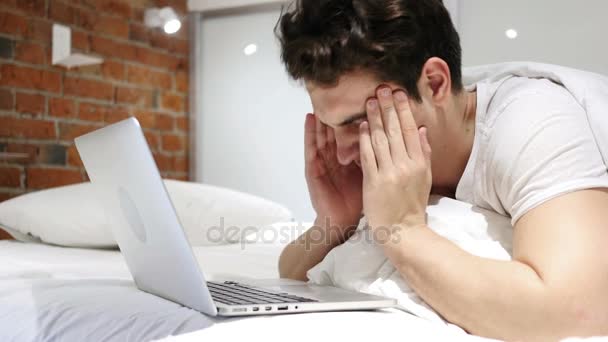 Dolor de cabeza, hombre cansado trabajando en el ordenador portátil en la cama
 - Imágenes, Vídeo