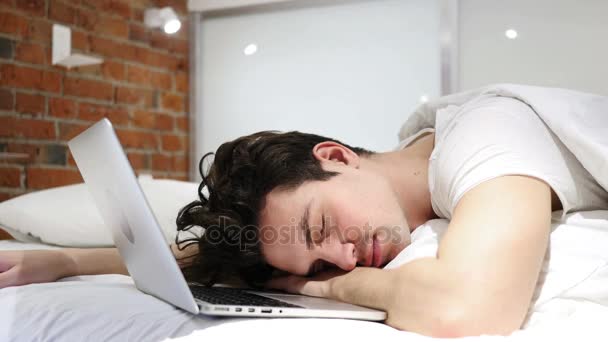 Hombre durmiendo en la cama cerca del ordenador portátil, después del trabajo
 - Metraje, vídeo