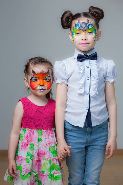 Little girls sister with rasskrashennymi faces isolated on gray background - 写真・画像
