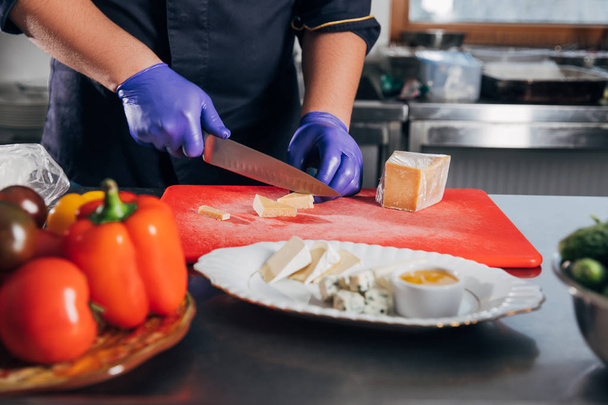 cropped shot of chef slicing cheese at workplace in restaurant - Foto, Bild