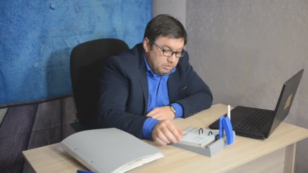 businessman in glasses sitting at table with laptop typing text - Video, Çekim