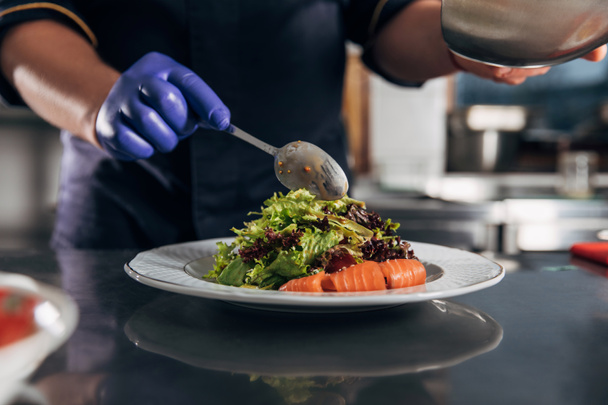 cropped shot of chef pouring sauce onto salad from spoon - Foto, Imagem