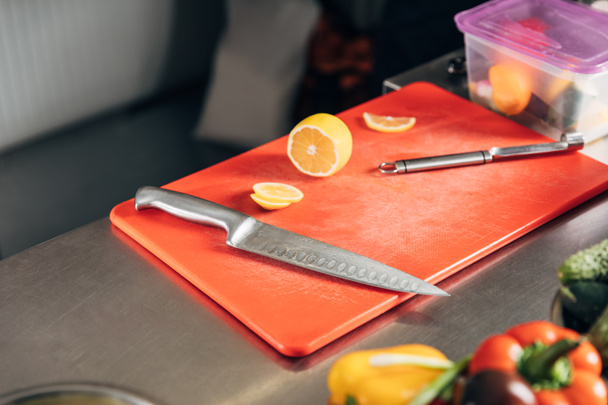cutting board with knife and halved lemon at restaurant kitchen - Фото, изображение