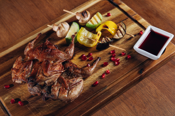 close-up shot of roasted quail with vegetables served on wooden board - Photo, Image
