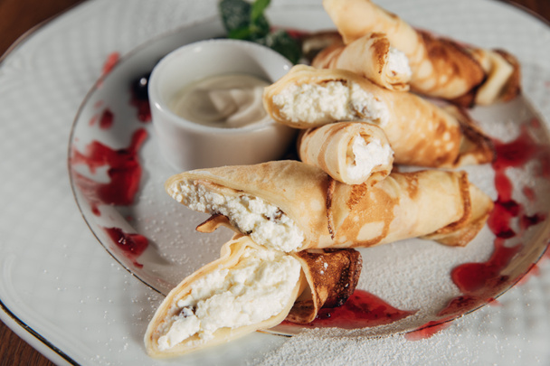 close-up shot of rolled crepes with cottage cheese served on white plate with jam - Foto, Imagem