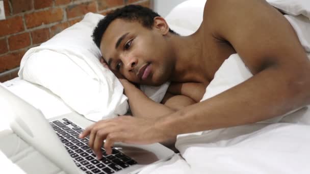 Αφρικανική άνθρωπος που εργάζονται για το Laptop, ξαπλωμένη στο κρεβάτι για υπόλοιπο - Πλάνα, βίντεο
