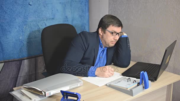 businessman in glasses sitting at table with laptop typing text - Metraje, vídeo