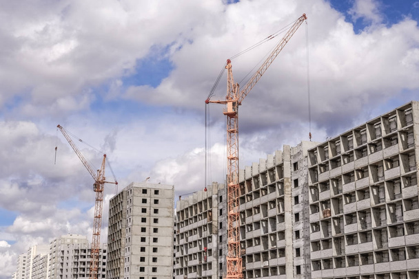 Construction cranes and multi-storey houses under construction - Foto, afbeelding