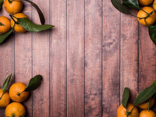 Fresh Mandarin or tangerine with stems and leaves on a brown wooden background copy space - Foto, Imagem