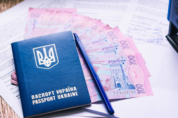 Passeport international ukrainien avec hryvnias sur fond de document. Monnaie, documents, timbres et passeports ukrainiens
. - Photo, image