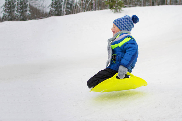 Kid vuela por una colina en el plato para conducir en la nieve
 - Foto, Imagen