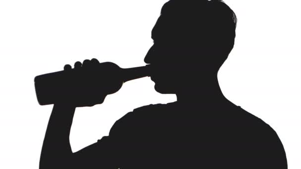 silueta mladý muž nepije alkohol z láhve izolovaných na bílém pozadí - Záběry, video