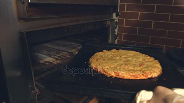 Kochen von Pizza. Zeitlupen.Frauenhände nehmen Pizza aus dem Ofen und übertragen sie auf das Schneidebrett.Die gekochte Pizza dreht sich auf dem Brett. - Filmmaterial, Video