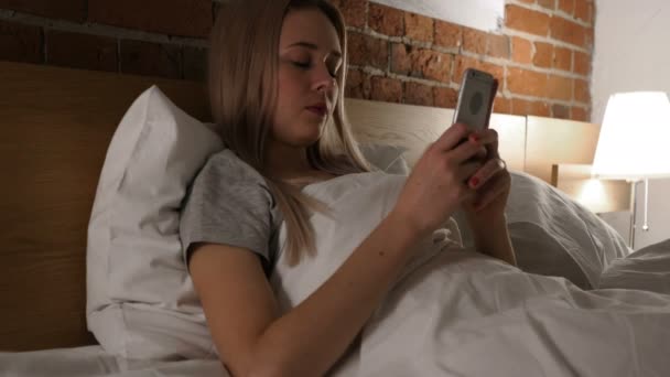 Woman in Bed Browsing, Scrolling on Smartphone at Night - Materiał filmowy, wideo