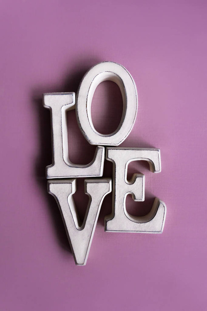 Wooden letters forming word LOVE lying on violet surface - Foto, Bild