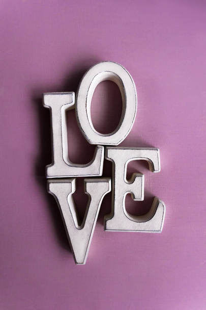 Wooden letters forming word LOVE lying on violet surface - Φωτογραφία, εικόνα