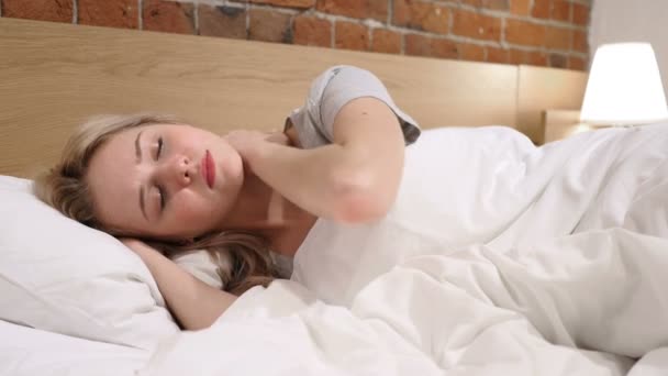 Zmęczona kobieta z ból w szyi leżącego w łóżku po stronie - Materiał filmowy, wideo