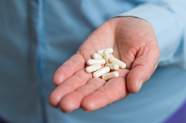 Cápsulas de medicamentos blancos de glucosamina, píldoras de suplementos saludables en la palma de la mano mujer
. - Foto, Imagen