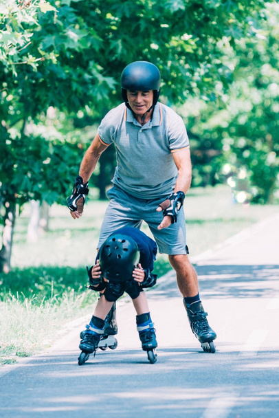 Grandfather and grandson having fun, roller skating in the park - Photo, Image