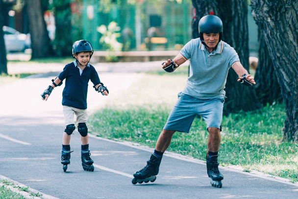 Grandfather teaching grandson roller skating in the park - Photo, Image