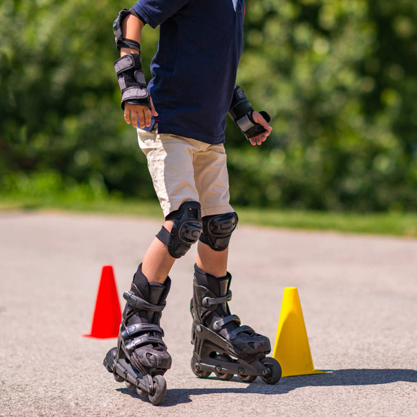 Мальчик тренируется кататься на роликовых коньках в парке
  - Фото, изображение