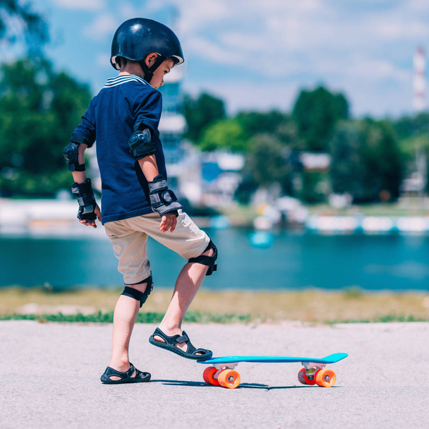 Petit garçon apprenant le skateborading dans le parc au bord du lac
 - Photo, image