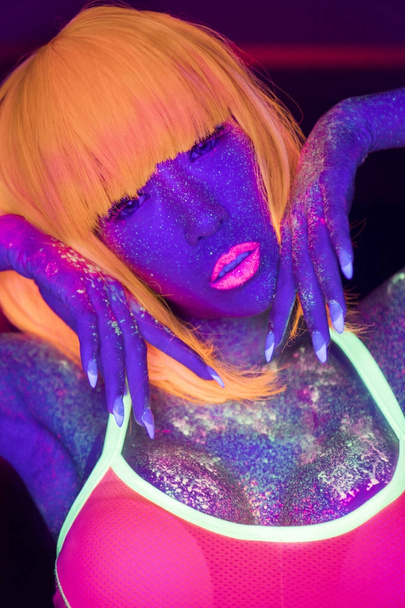 Closeup woman face with fluorescent make up in orange wig, creative makeup look great for nightclubs. Halloween party, shows and music concept - Foto, Imagem