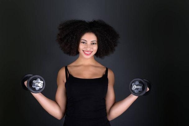 Mujer afroamericana muscular con mancuernas. - Foto, imagen