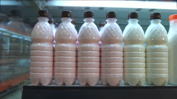 Zure melkproducten in de supermarkt. Horizontale pan. De camera beweegt langs de plank waarop flessen van melk en zuivelproducten zijn. - Video