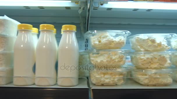 Кисло-молочные продукты в супермаркета.Горизонтальное пан.Камера движется вдоль полки, на которой есть творог, молоко, кефир и йогурт
. - Кадры, видео
