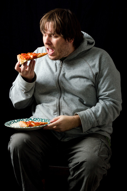 Hombre con sobrepeso comiendo una pizza
. - Foto, imagen