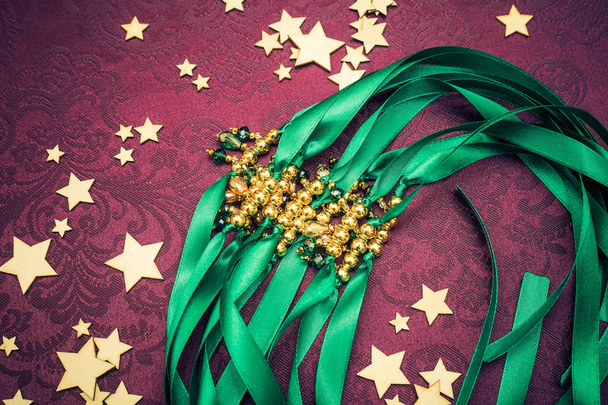 Beautiful sparkling glamorous embellishments on the ribbon, bridesmaids necklaces, emerald and gold color, purple background, party decorations - Photo, Image